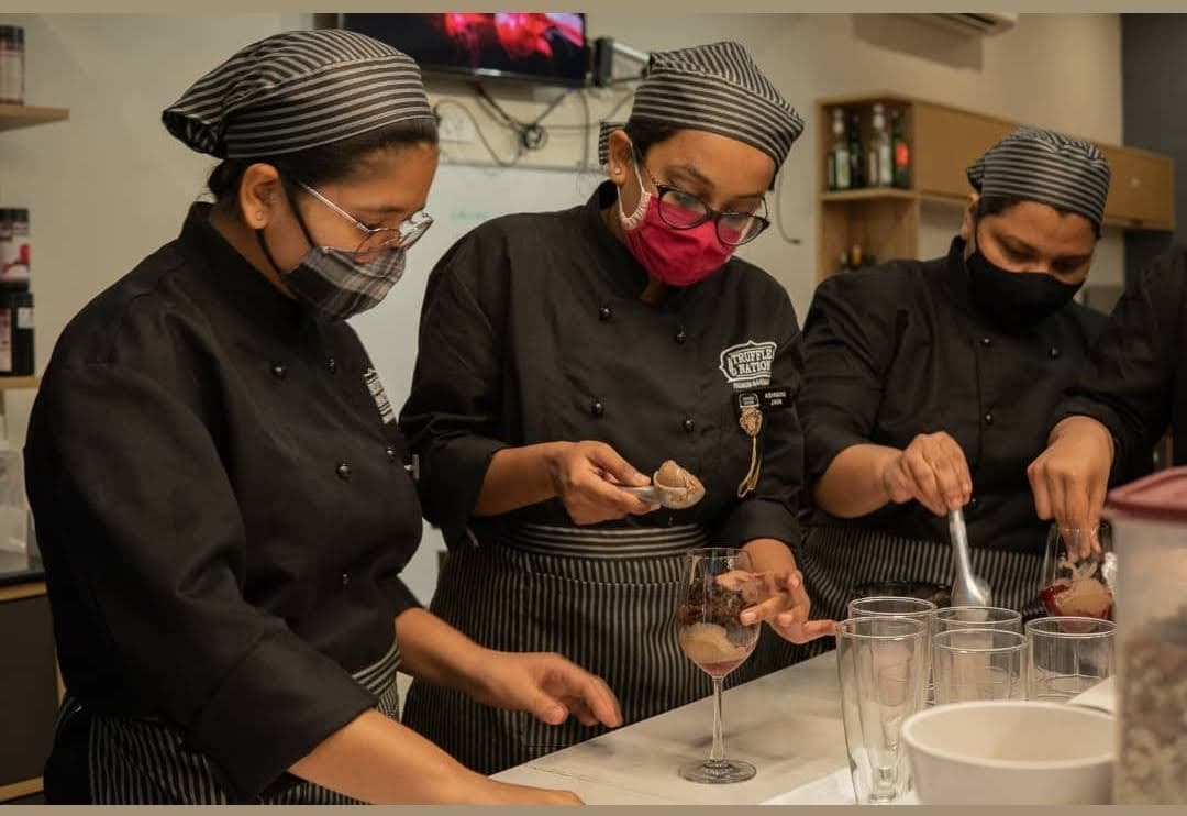 Chef team in Truffle Nation uniforms plating desserts in the teaching kitchen